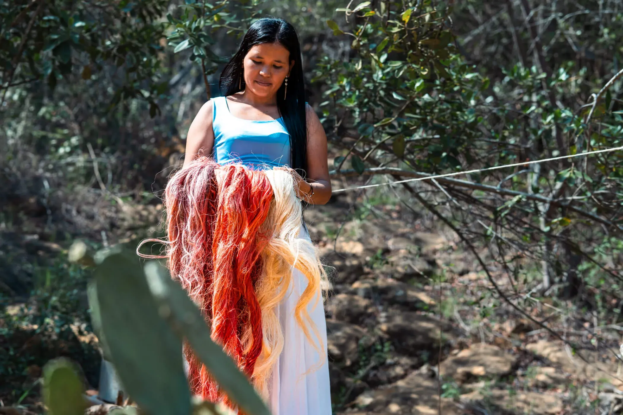 A woman holding naturally dyed fibres outdoors for Nodomondo.