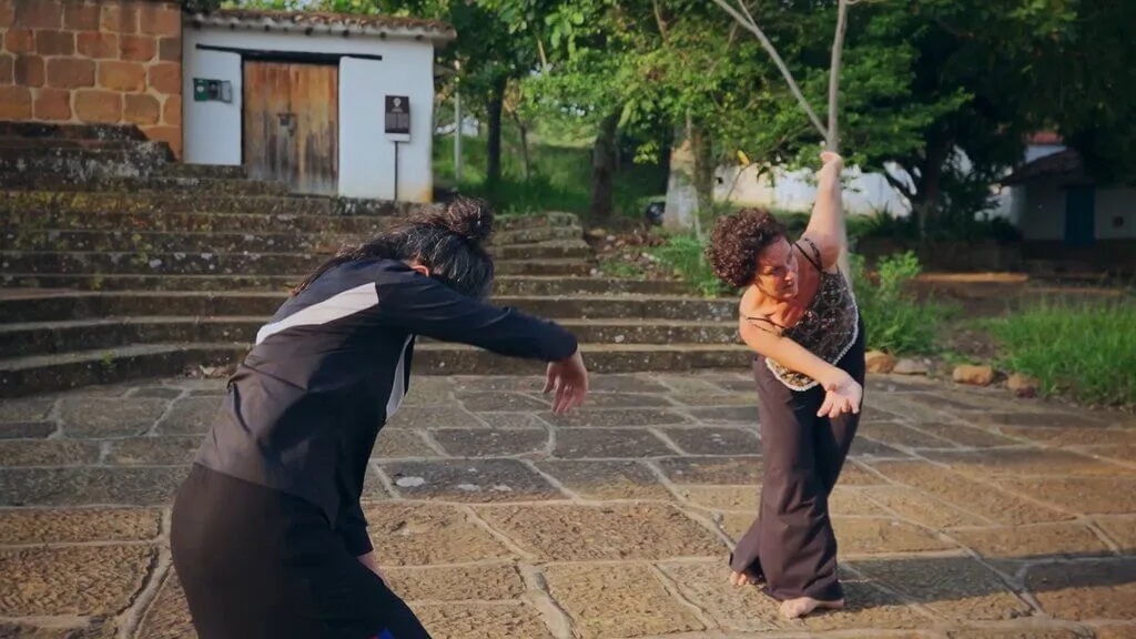 Two dancers performing outdoors on a stone plaza near steps and a building.
