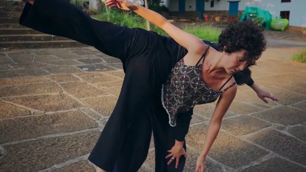 Dancers Cata and Carmen in a dynamic pose, one lifting the other on a stone surface.