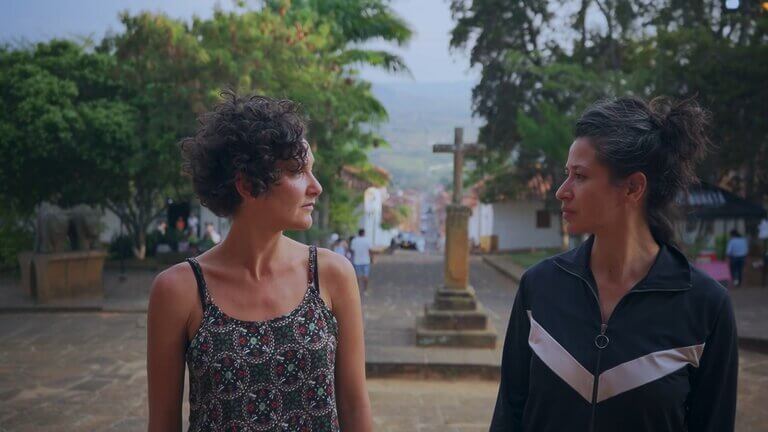 Cata and Carmen stand near a stone cross overlooking a Colombian town.