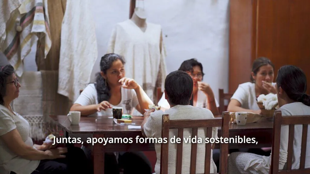 Group of women at a table, supporting sustainable lifestyles. Text: "Juntas, apoyamos formas de vida sostenibles.