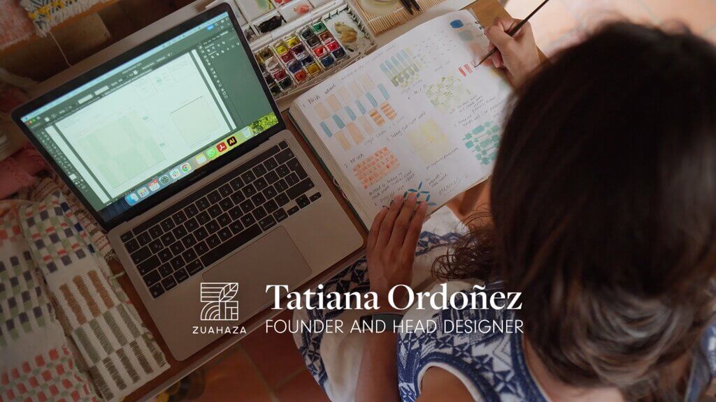 Tatiana Ordoñez, founder and head designer of Zuahaza, working on design sketches with laptop and watercolors.