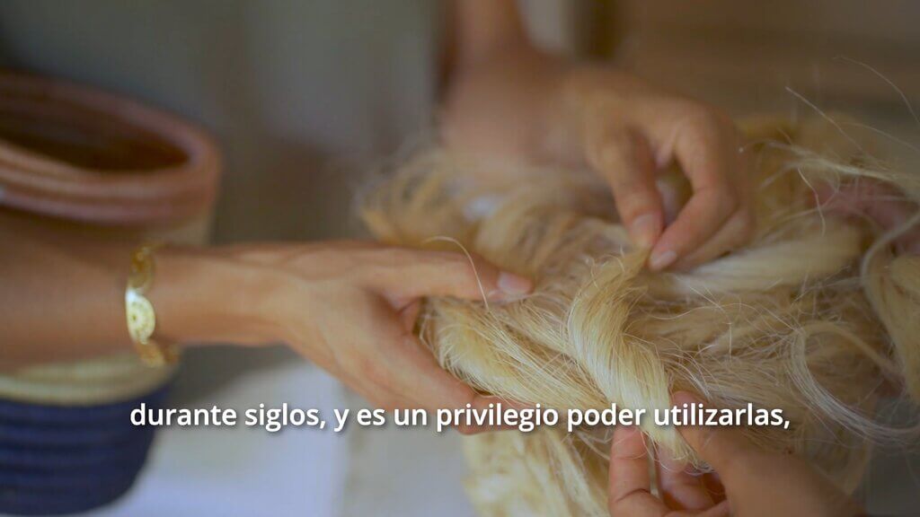 Hands working with natural fibers, possibly for Zuahaza crafts