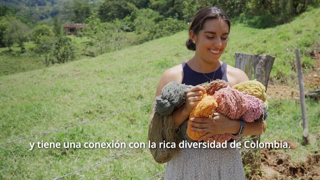 Woman holding colorful yarn in a field, representing the rich diversity of Colombia.
