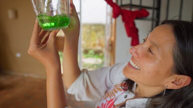 Woman smiling, holding up glass of green liquid in Casa Común.
