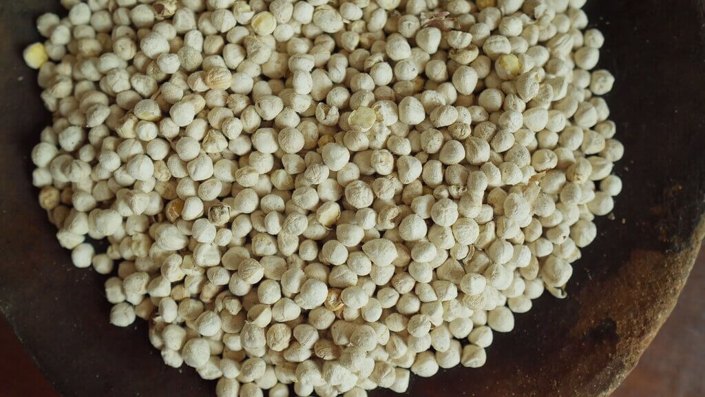 Pile of dried achiote seeds in a wooden bowl, ready for cooking.