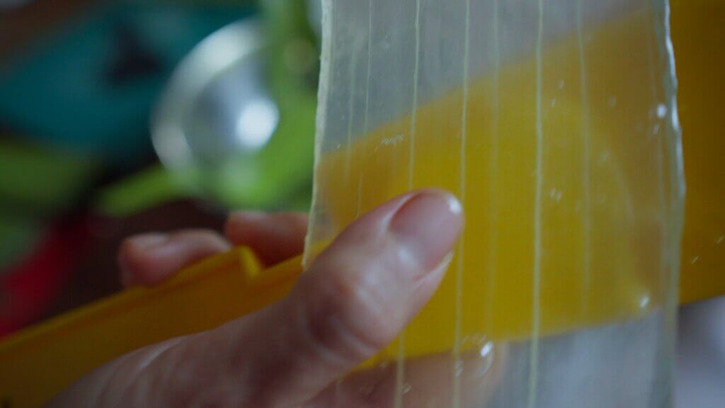 Hand holding a yellow toy xylophone with visible strings, close-up detail.