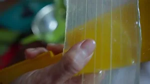 Hand holding a yellow toy xylophone with visible strings, close-up detail.