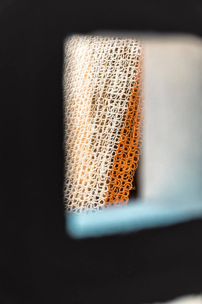 Close-up of a textured, interwoven Nodomondo mat with orange and white tones.