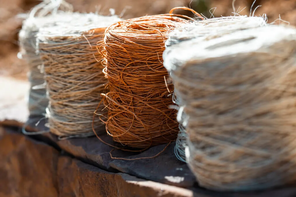 Spools of natural fiber twine in neutral and brown tones, sitting on a stone surface.