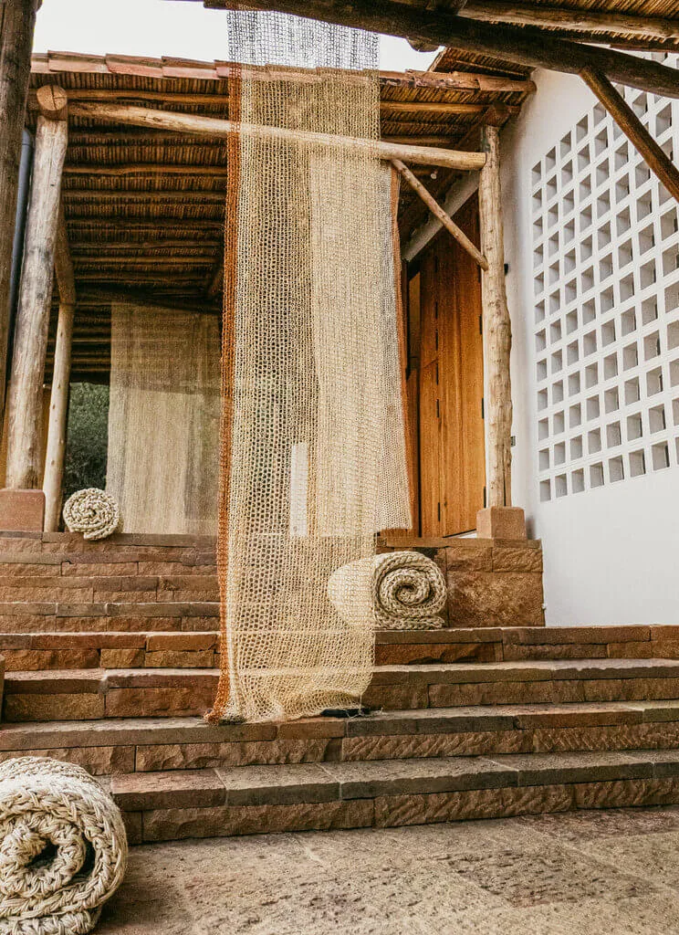 Nodomondo: Rustic architecture with woven textiles and stone steps, creating an inviting entrance.