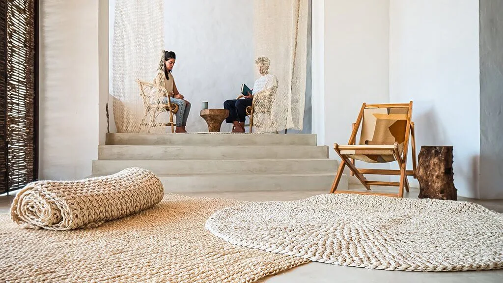 Nodomondo-inspired room with neutral tones, woven rugs, and relaxed seating for two.