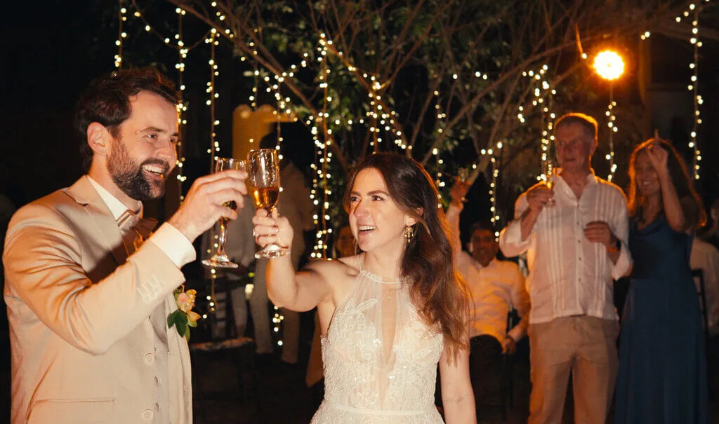 Mariana and Alex toasting at their wedding reception under string lights.