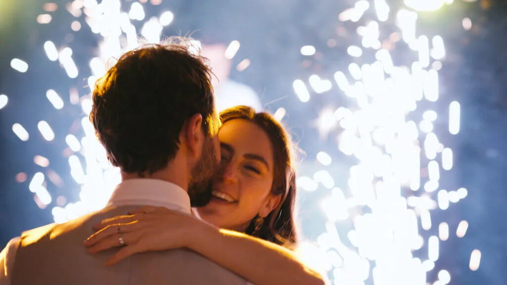 Mariana and Alex embrace during their wedding dance, with sparklers creating a magical backdrop.