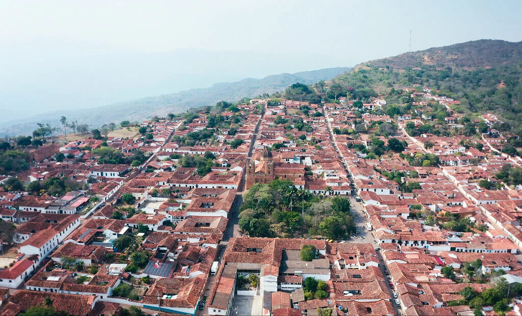 Aerial view of a charming town with red tile roofs nestled at the foot of a mountain.