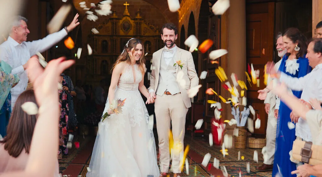 Mariana and Alex wedding exit, showered with confetti. Happy couple leaving church.
