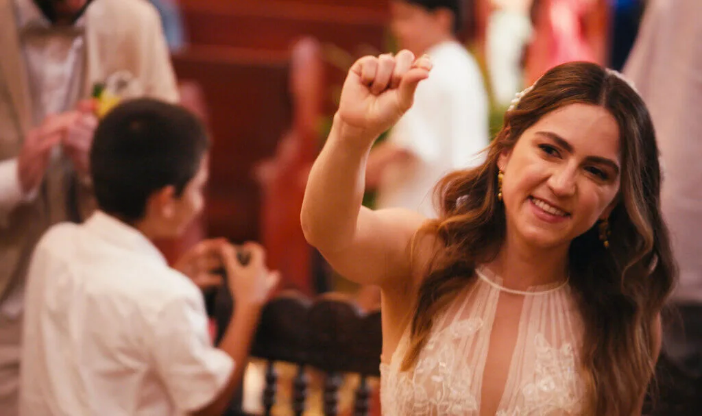 Bride Mariana joyfully tosses her wedding bouquet at the reception after marrying Alex.