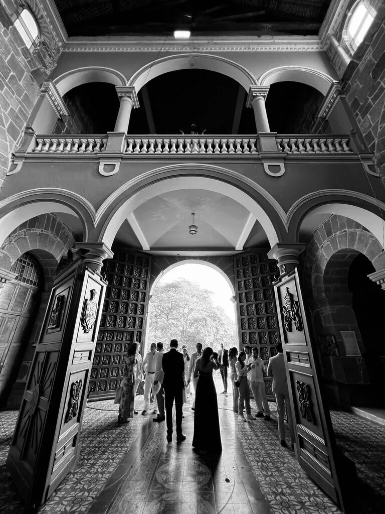 Mariana & Alex wedding: A couple stands at the entrance of a grand church, surrounded by guests.