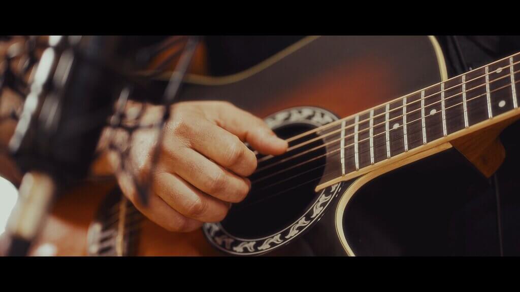 Close-up of a person playing an acoustic guitar, recording music