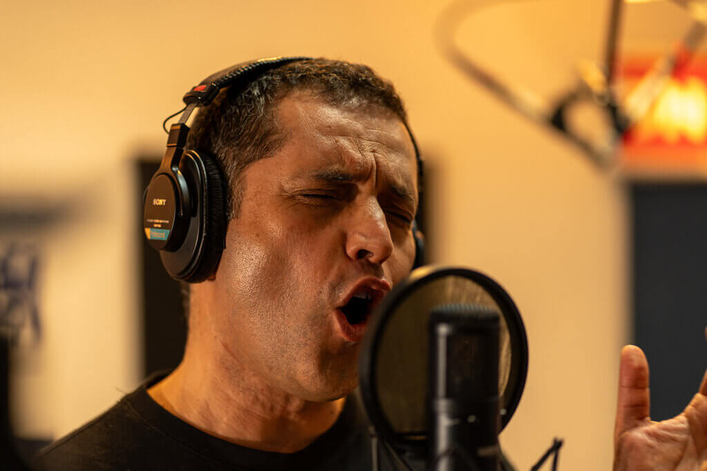 Man singing with headphones in a recording studio. Passionate performance.