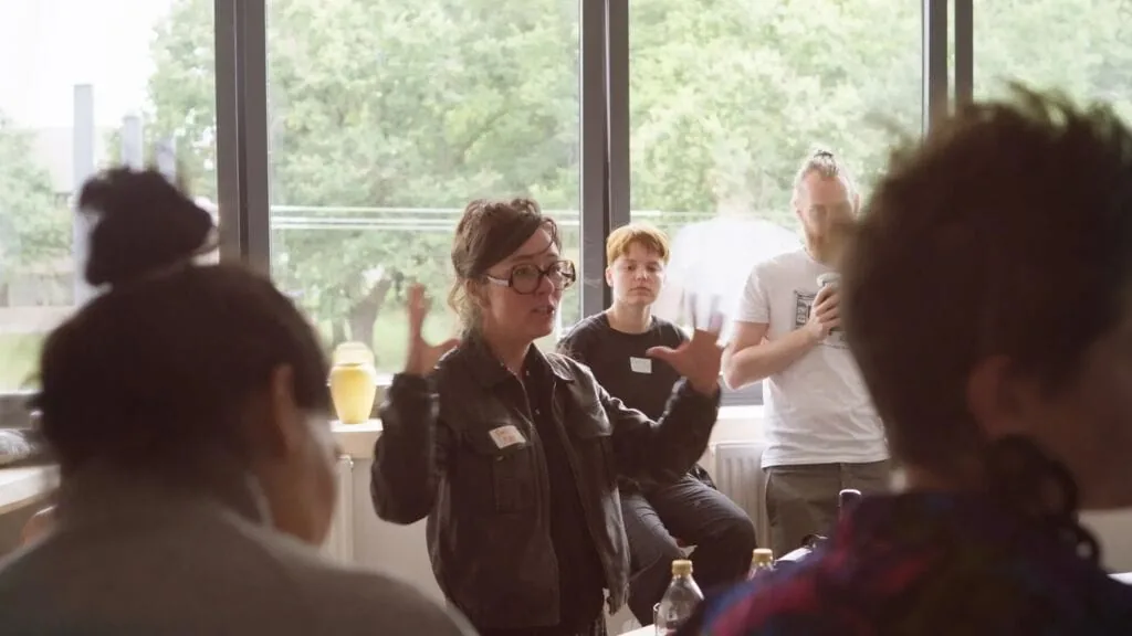 Group discussion with a woman gesturing, possibly at a Sindup workshop.