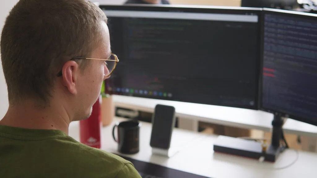 Programmer working on dual monitors, likely related to Sindup.