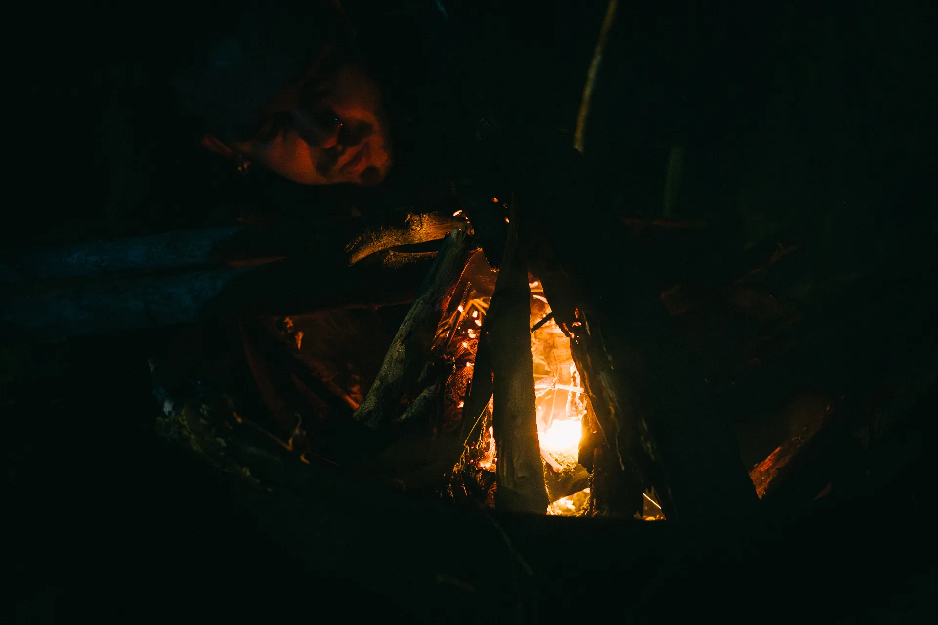 Person watching a campfire burning in the dark. Camping in El Páramo.